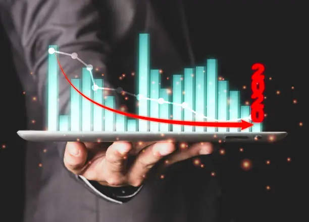 Photo of Closeup of executive businessman holding and giving financial graph or chart 2020 year which economic down from trade war and COVID-19. Analysis business of stock investment concept.