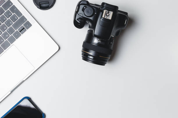 istock Photographer's workplace on a white background. Modern laptop, digital camera, lens, battery, smartphone. Minimalism. Top view. Copy space. Equipment for the photographer. The concept of freelancing 1209678979
