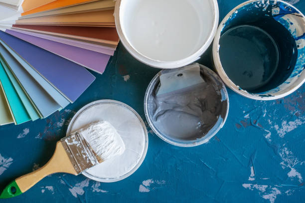 Choose a paint color for the walls. Spatula for painting and wall putty and background in a tray next to a bucket of putty.. Create a background stock photo