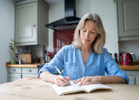 Portrait of a beautiful adult woman at home writing on her journal - lifestyle concepts