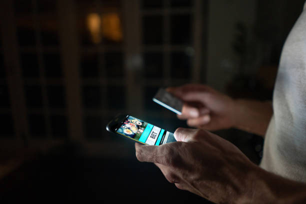 man betting online at home on his cell phone - gambling imagens e fotografias de stock