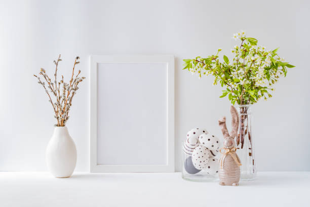istock Home interior with easter decor. Mockup with a white frame and spring flowers in a vases on a light background 1209689068