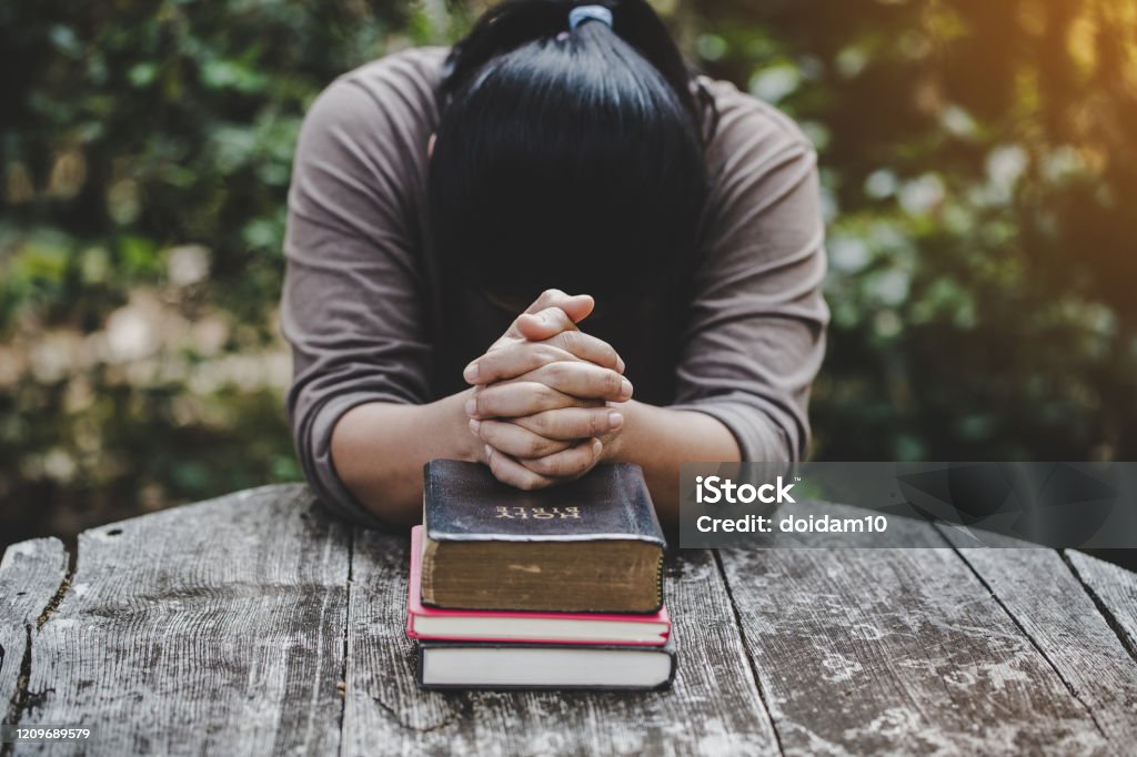 Hands folded in prayer on a Holy Bible in church concept for faith Hands folded in prayer on a Holy Bible in church concept for faith, spirituality and religion, woman praying on holy bible in the morning. woman hand with Bible praying. Praying Stock Photo
