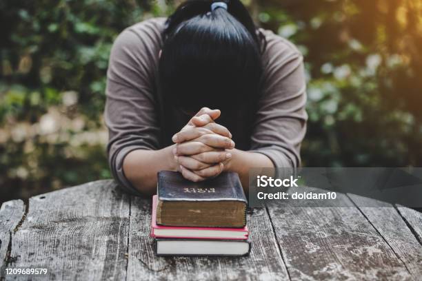 Hands Folded In Prayer On A Holy Bible In Church Concept For Faith Stock Photo - Download Image Now