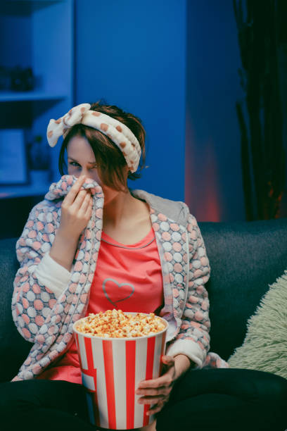 istock Young woman cry while watching a very moving movie with popcorn at night 1209692507
