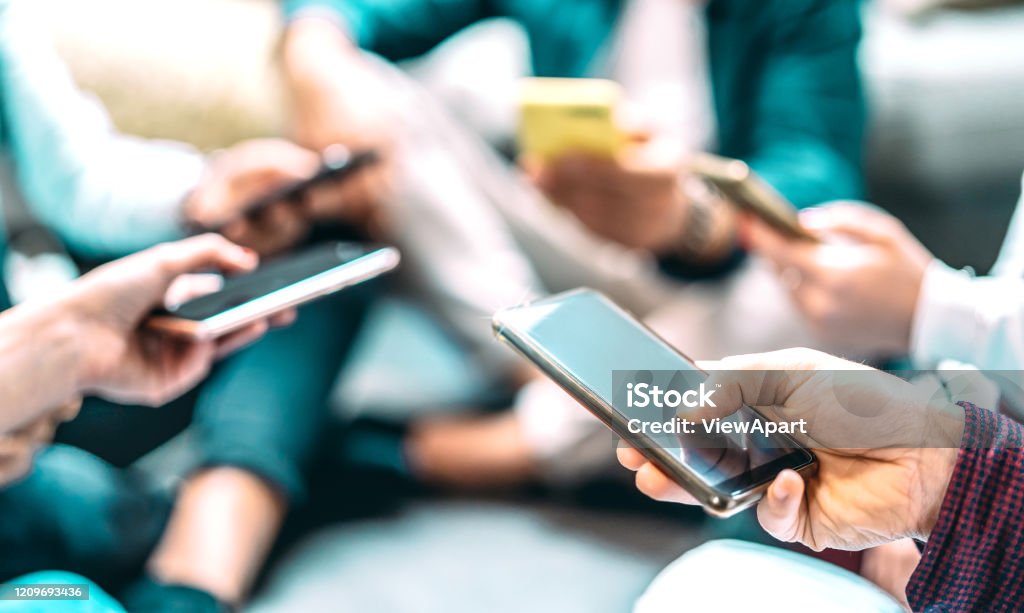 Close up of people using mobile smart phones - Detail of friends sharing photos on social media network with smartphone - Technology concept and cellphone culture with selective focus on right hand Social Media Stock Photo