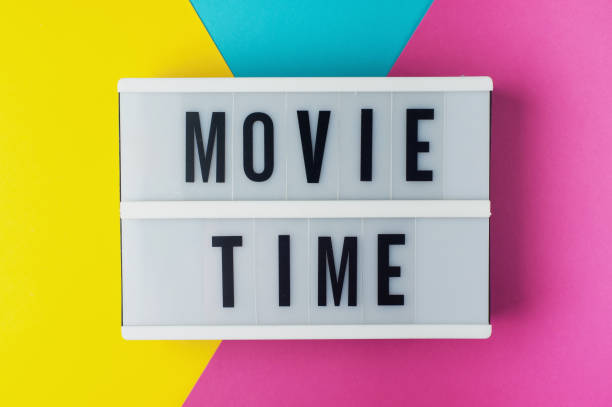 istock Movie time - text on a display lightbox on blue, yellow and pink background. 1209693504