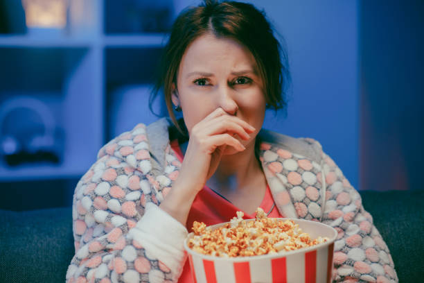 istock Young woman cry while watching a very moving movie with popcorn at night 1209694209