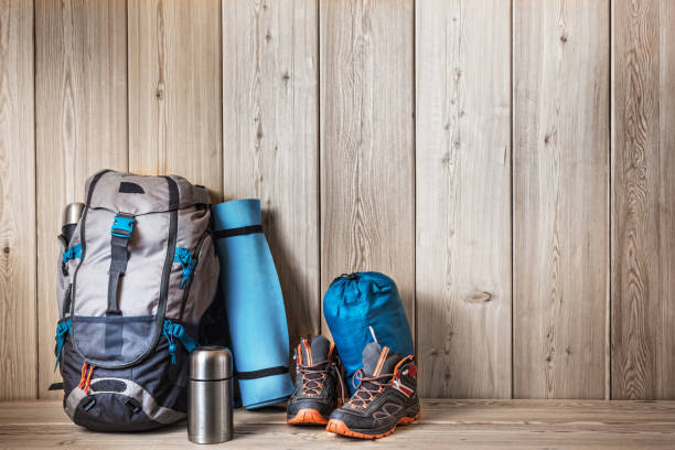 camping equipment, shoes, a backpack and a thermos on a wood background - tree stream forest woods imagens e fotografias de stock