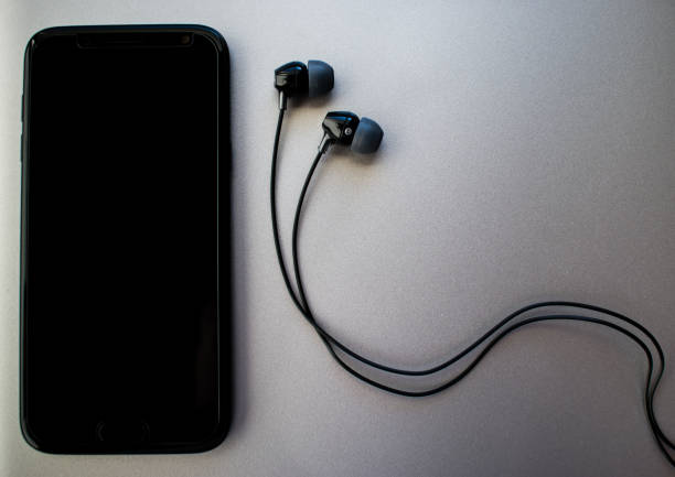 istock Black mobile phone and black earphones on silver background 1209699975