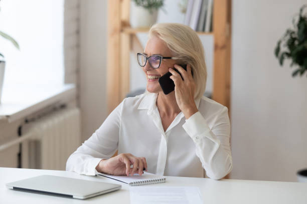 Aged businesswoman talking on smartphone enjoy conversation with client
