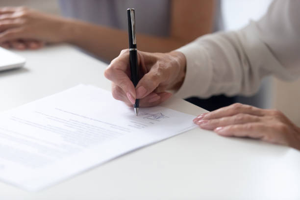 istock Close up view female hand signing contract legal document 1209703841
