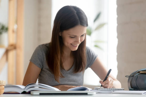 istock Student girl studying with handbook do homework seated at desk 1209703878