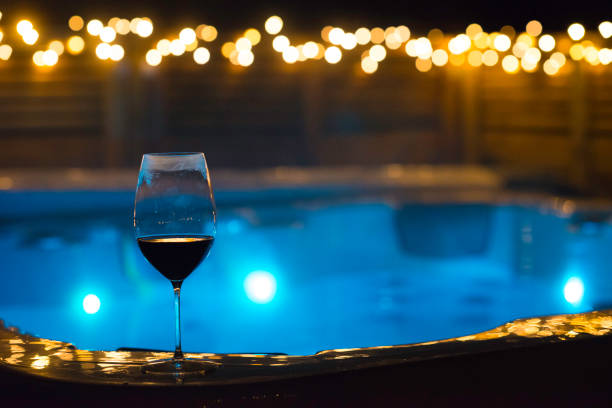 Wine glass in front of spa bath surrounded by lights at night