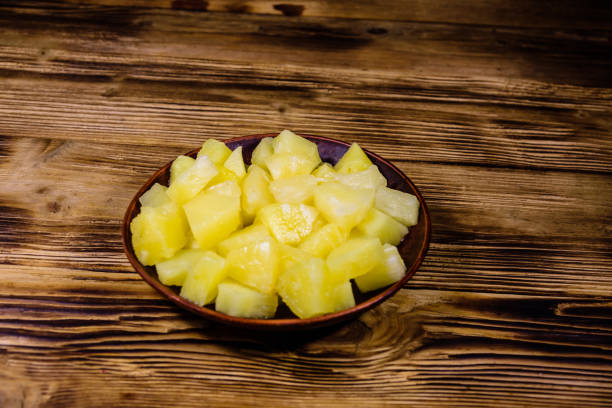 istock Ceramic plate with chopped canned pineapple on wooden table 1209709588