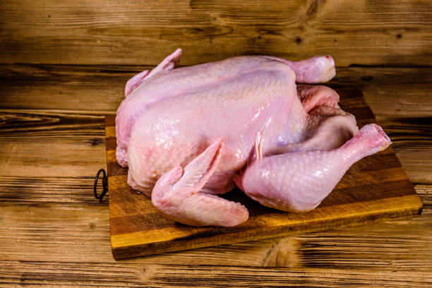 istock Wooden cutting board with the whole uncooked chicken 1209709599