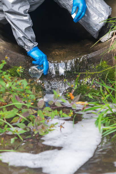istock environmental laboratory specialist in protective suit and mask in a gutter pours water into a flask to study the level of pollution, close-up 1209709740