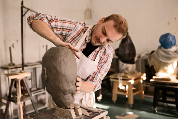 istock Sculptor working on his clay head sculpture in workshop studio 1209715039