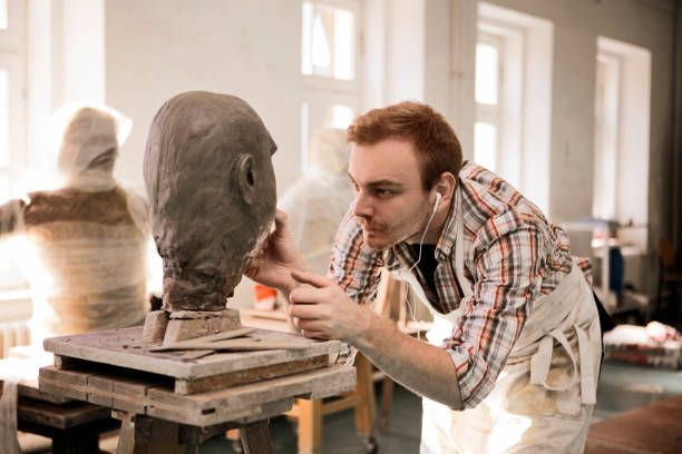 istock Sculptor working on his clay head sculpture wearing headphones 1209715044