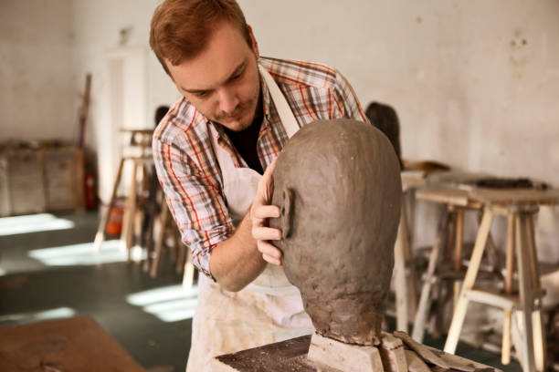 istock Sculptor working with clay sculpting a head 1209715140