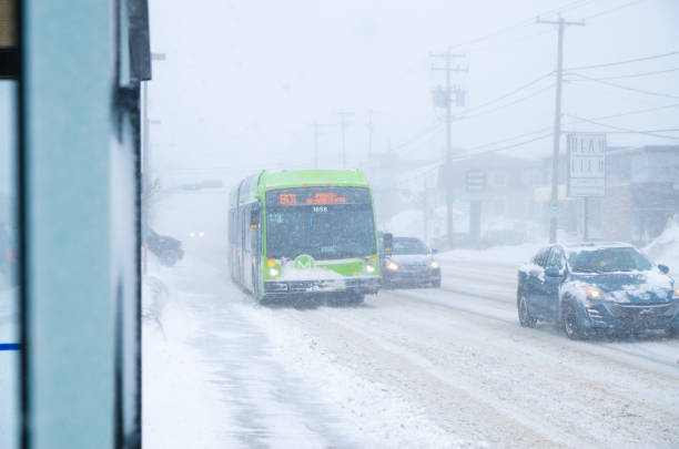 Front view of cars and bus passing by on suburb boulevard during a day of snowstorm in Quebec city
