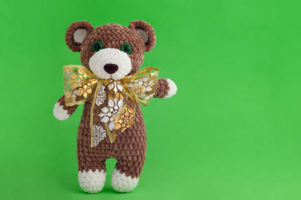 istock Children's knitted toy bear with bow on a green background 1209729543