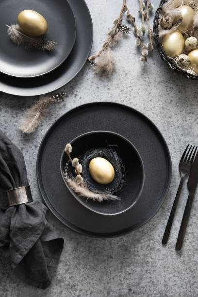 istock Easter table setting with black and golden decor on grey. Top view. 1209731488