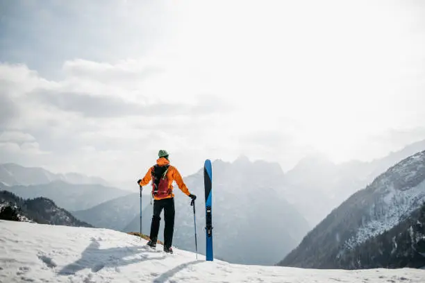 Photo of Hiker enjoying the views in the mountains before skiing back to the valley