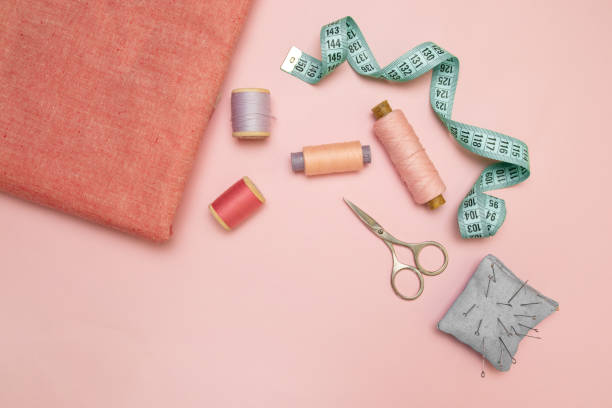 Top view of sewing machine with accessories for sewing, scissors and a measuring tape on pink background. Vertical position Top view of sewing machine with accessories for sewing, scissors and a measuring tape on pink background seamed stock pictures, royalty-free photos & images
