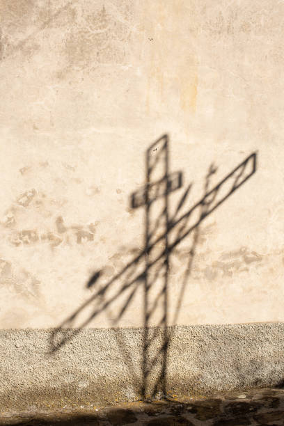 istock Shadow of a metal cross falling on  exterior wall 1209734028