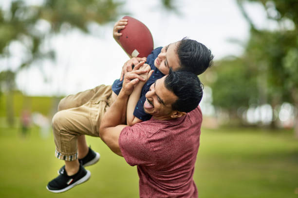 aktive hispanische familie spielt fußball im miami public park - child american football football sport stock-fotos und bilder