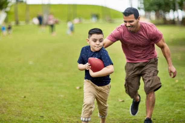 istock Hispanic Father Pursuing Determined Young Son with Football 1209737065