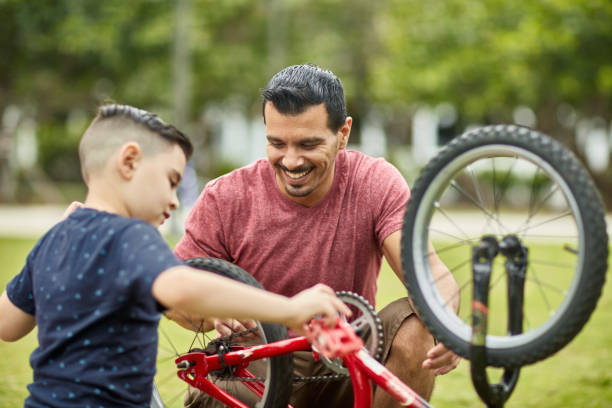istock Smiling Hispanic Father Teaching Son About Bicycle Repair 1209737066