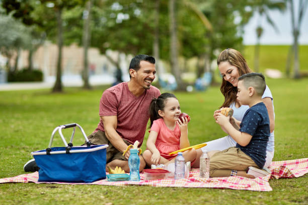 glückliche junge hispanische familie verbringt zeit zusammen im park - picknick stock-fotos und bilder