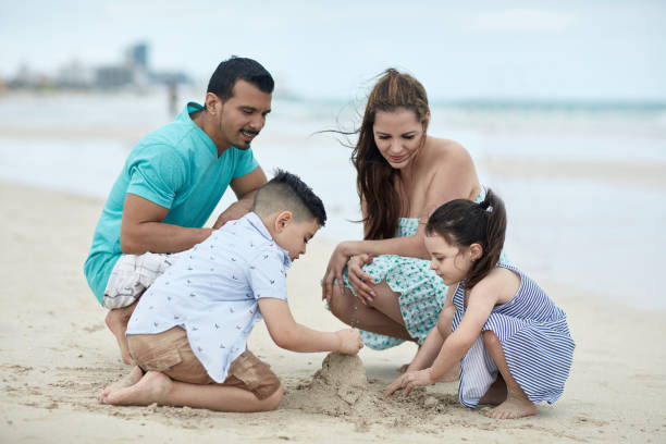 istock Relaxed Hispanic Parents Watching Children Build Sandcastle 1209737124