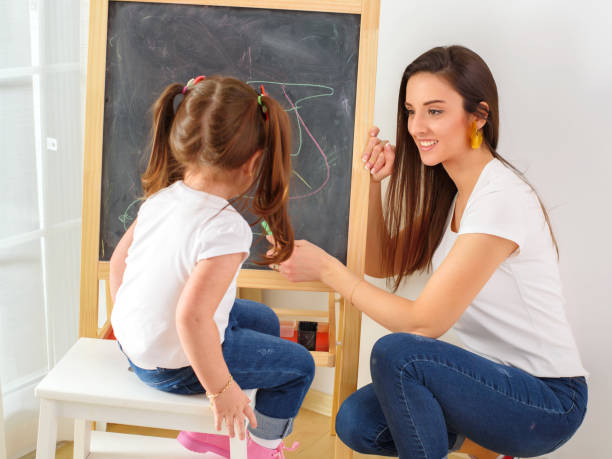 istock Mother and daughter drawing on the blackboard 1209737755