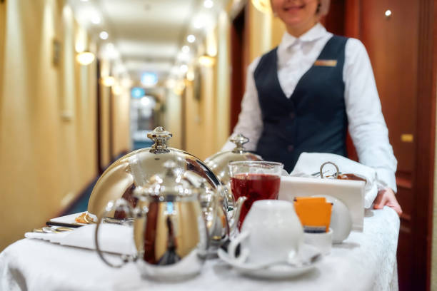 todo lo que necesitas. camarera en uniforme entrega de bandeja con comida en una habitación del hotel. servicio de habitaciones. enfoque en vajilla - edificio de hostelería fotografías e imágenes de stock