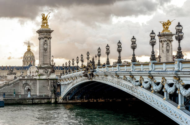 Scenic Alexander III bridge with ornate light posts and Dome des Invalides cathedral in a distance, Paris stock photo
