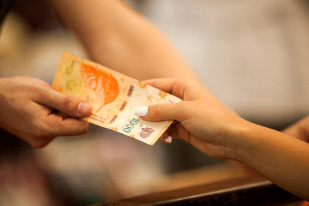 Woman paying in farmers market with Argentinian currency stock photo
