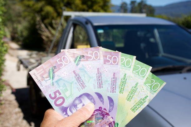 The Cost of a Car - NZD New Zealand Dollars The Cost of a Car Concept - NZD New Zealand Dollars with a Car in the Background out of Four. cash for cars stock pictures, royalty-free photos & images