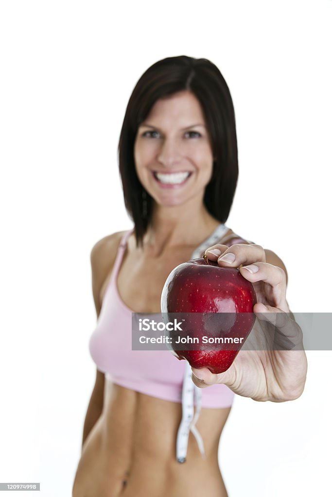 Woman holding apple selective focus Woman holding an apple wearing fitness clothing with a tape measure on her shoulder  20-29 Years Stock Photo