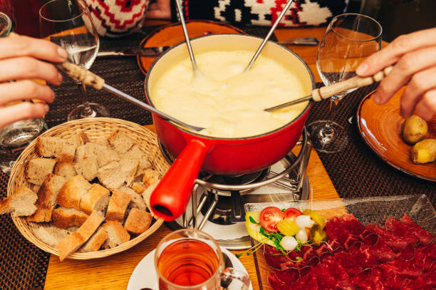 друзья едят сыр фондю в уютном традиционном швейцарском ресторане - fondue swiss culture winter cheese стоковые фото и изображения