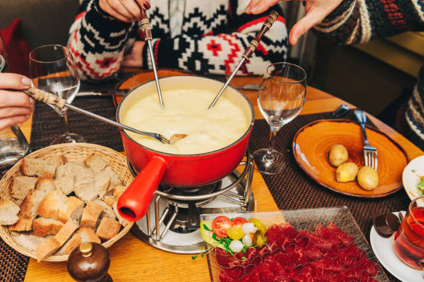 amis mangeant la fondue de fromage dans un restaurant suisse traditionnel confortable - culture suisse photos et images de collection
