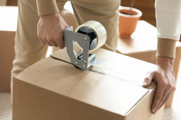 istock Close up of man packing box with adhesive tape 1209762644