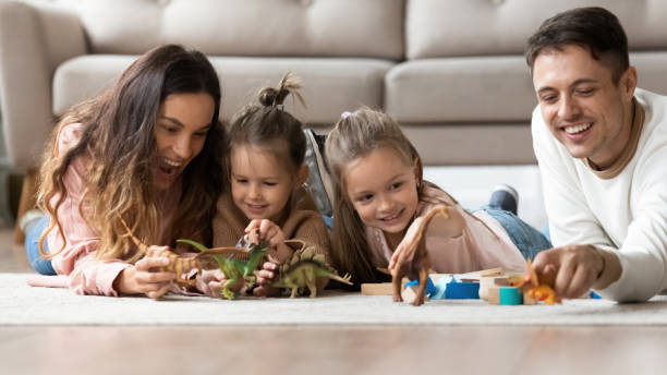istock Happy parents play with little daughters at home 1209762653