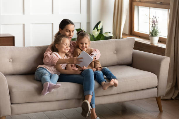 istock Loving young mom reading book with little daughters 1209762809