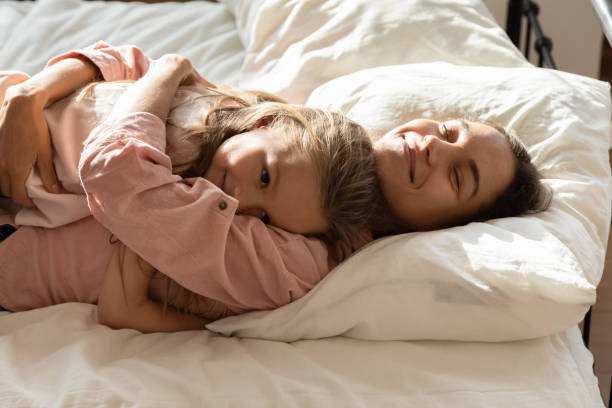 istock Loving mum cuddle relaxing in bed with little daughter 1209762937