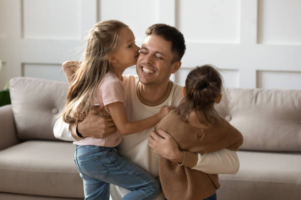 istock Little daughters kiss on cheeks happy young father 1209763462