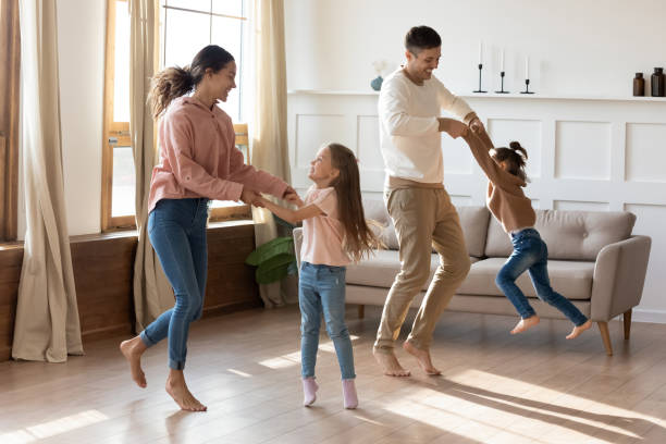 istock Happy parents dancing with small daughters in living room 1209763466