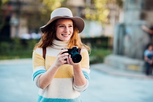 Portrait of a beautiful, young female tourist sightseeing and  photographing.